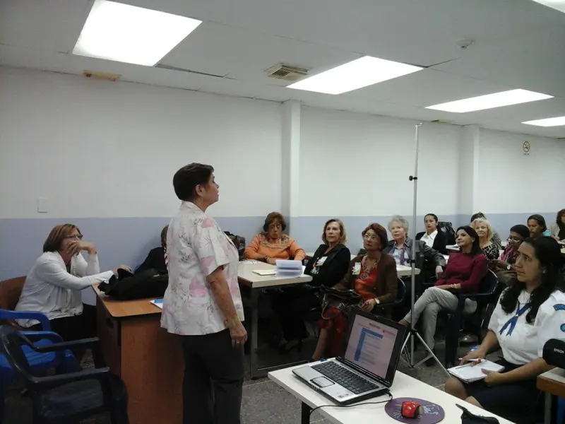 A facilitator leads a training workshop in front of a group of participants in a classroom