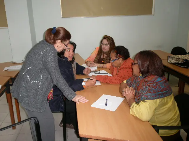 A facilitator working with a group of participants gathered around a work table